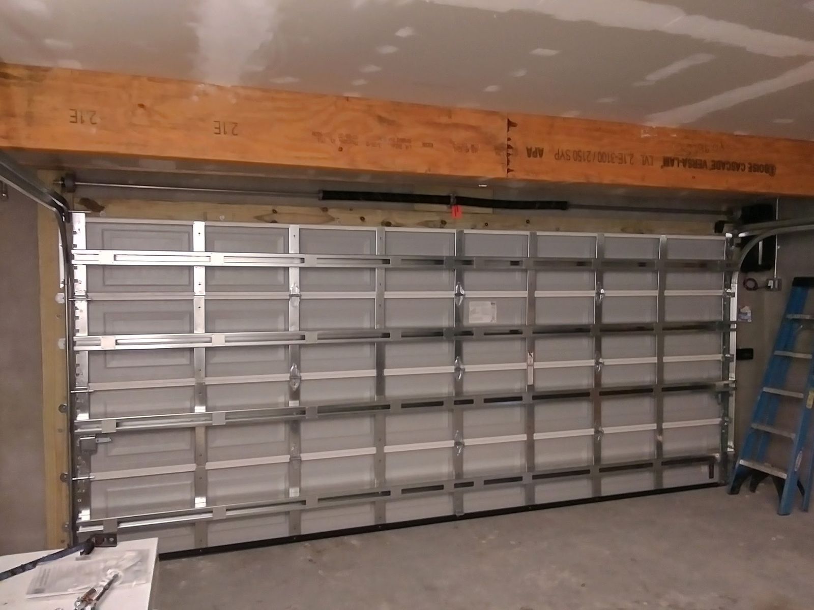 Interior of a garage door showing full-width struts, hinges, tracks, and rollers