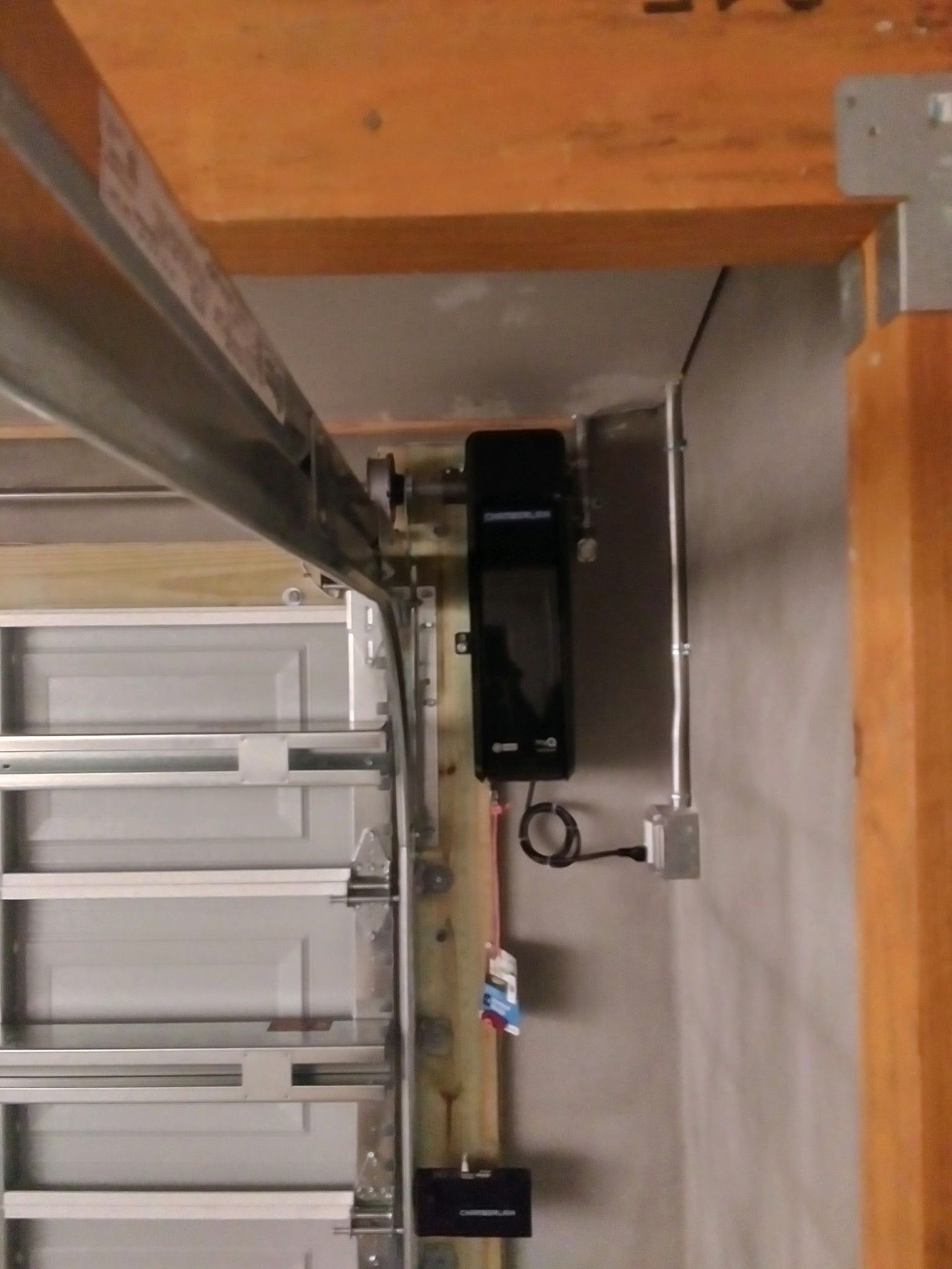 Black wall-mounted garage door opener installed next to the torsion bar