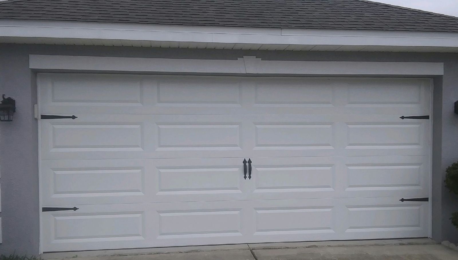 White double-car carriage-style garage door with black decorative hinges and handles