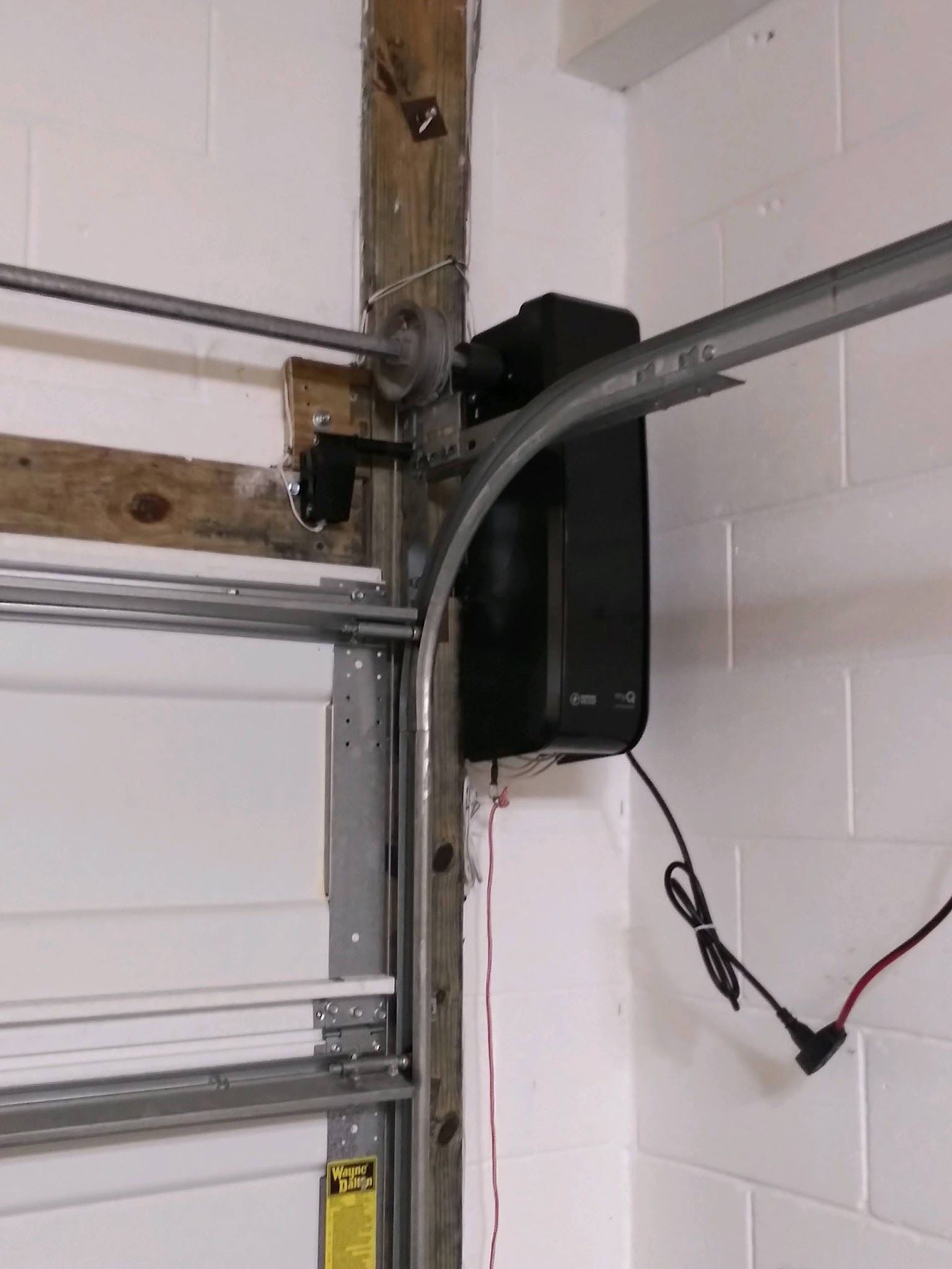 Wall-mounted garage door opener installed beside the door track