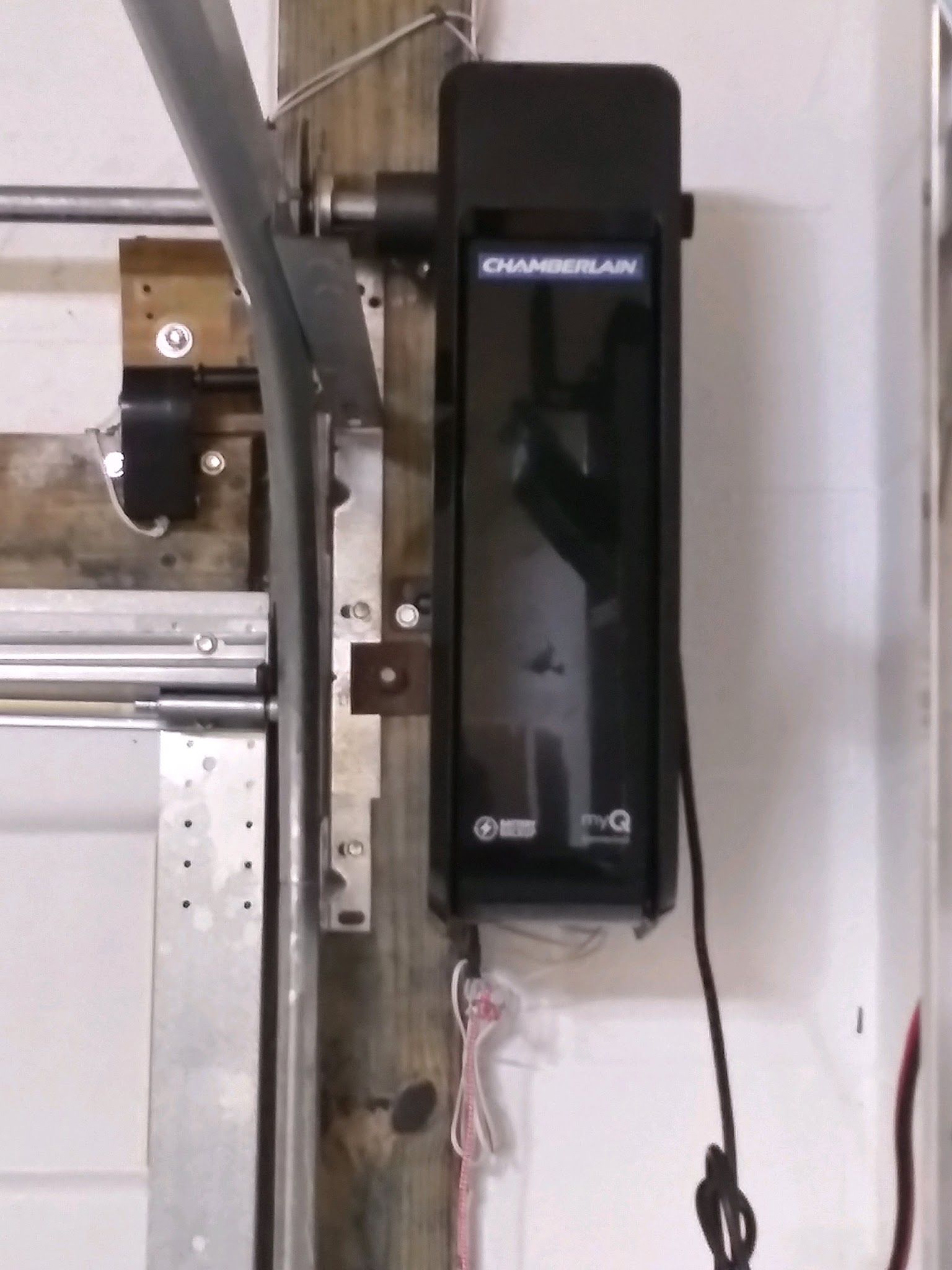 Close-up of a black wall-mounted garage door opener bolted to a wood post