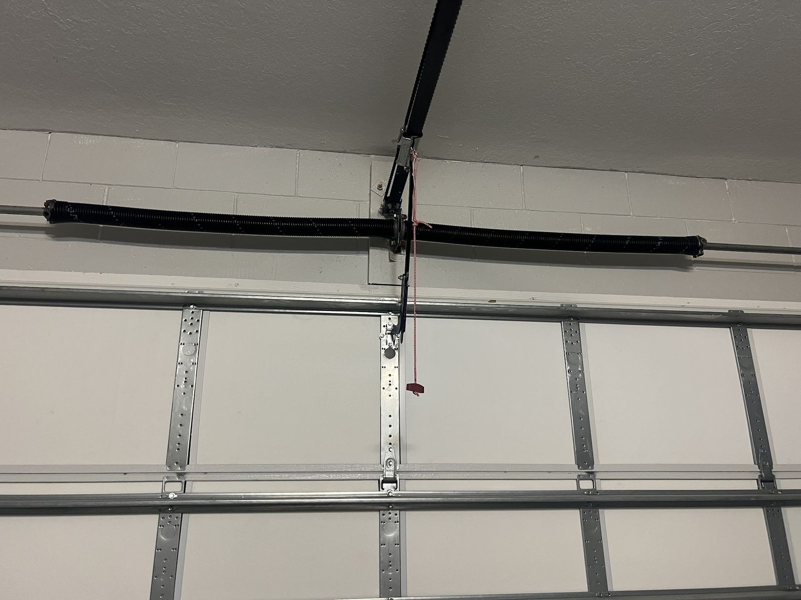 Two torsion springs on the header shaft above a white garage door