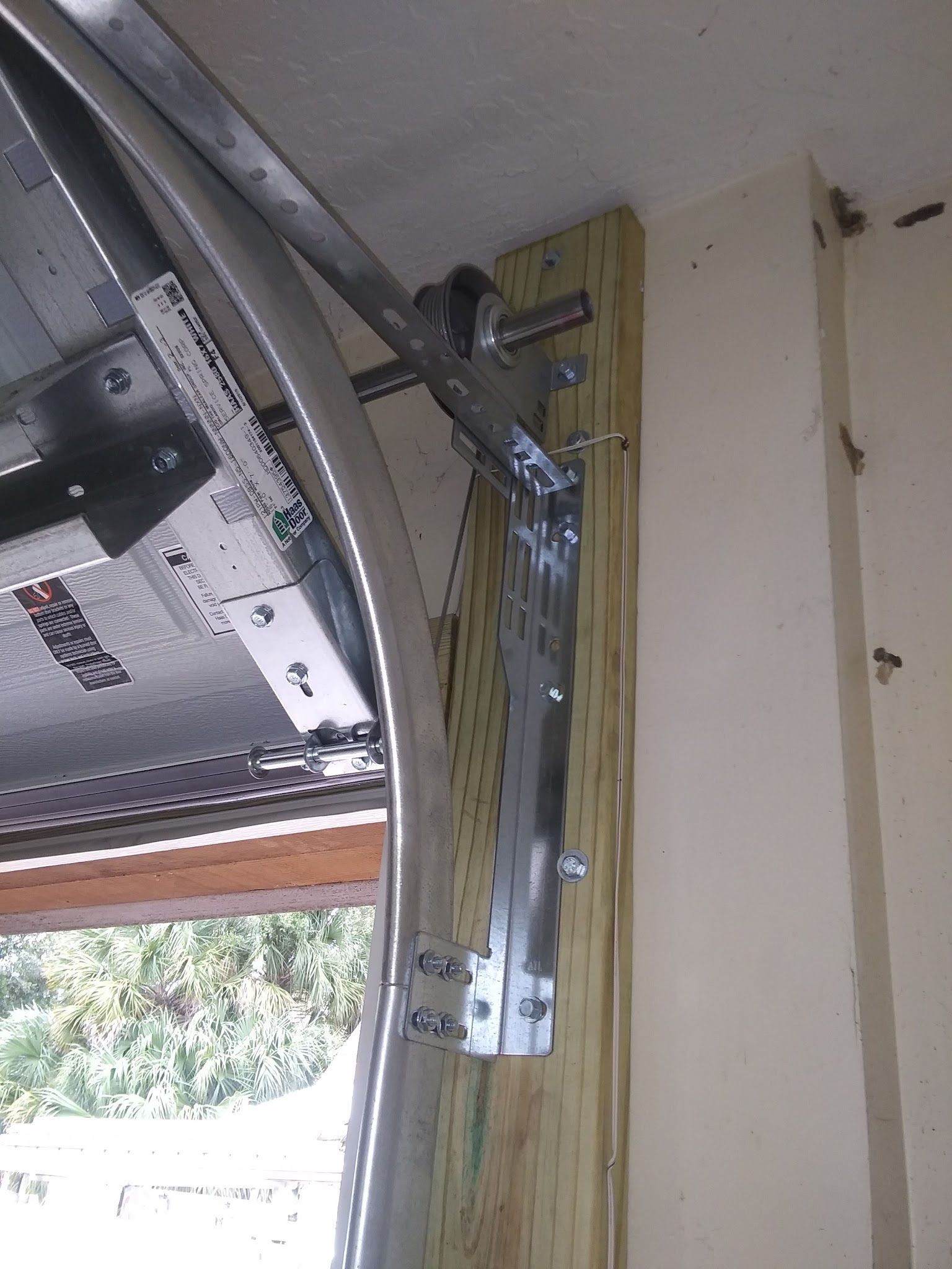 Garage door track, cable drum, and mounting hardware with the door partly open